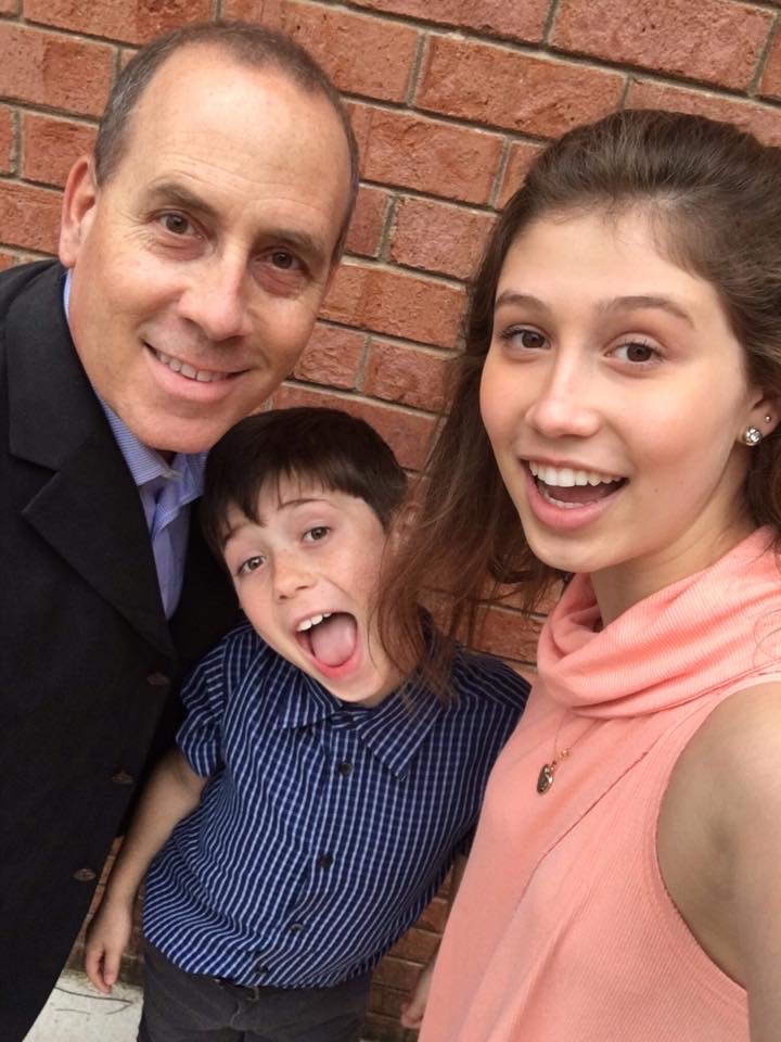 Father with son and daughter by a brick wall